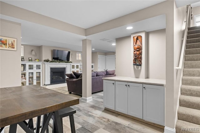interior space featuring a fireplace with raised hearth, recessed lighting, baseboards, and stairs