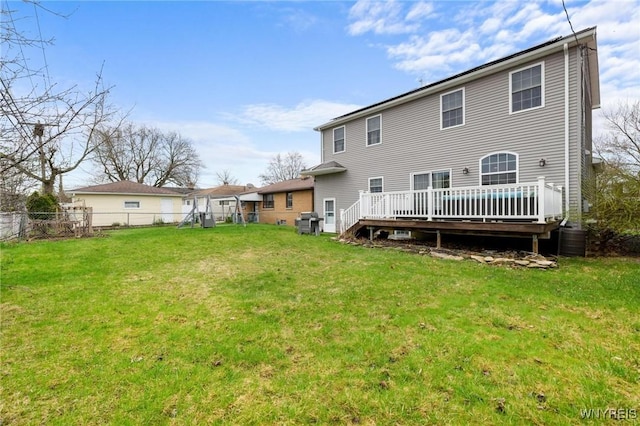 back of house featuring fence, a deck, and a lawn