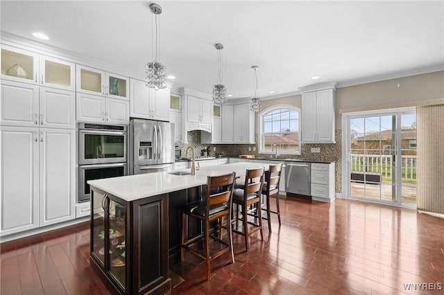 kitchen featuring tasteful backsplash, white cabinets, a sink, appliances with stainless steel finishes, and dark wood-type flooring