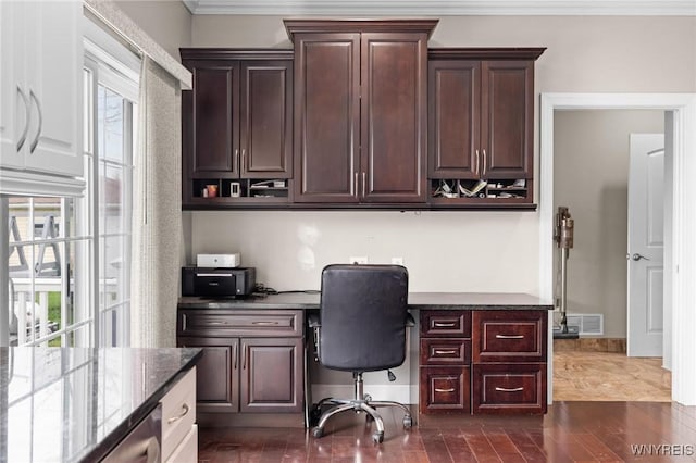 office with dark wood-type flooring, visible vents, ornamental molding, and built in study area