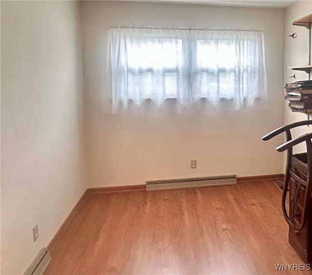 empty room featuring baseboard heating, baseboards, and wood finished floors