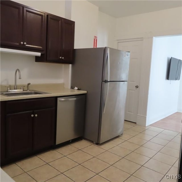 kitchen featuring dark brown cabinetry, stainless steel appliances, light countertops, and a sink