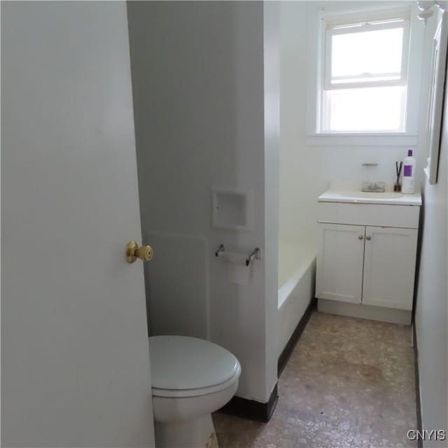 full bathroom with baseboards, a tub, toilet, and vanity