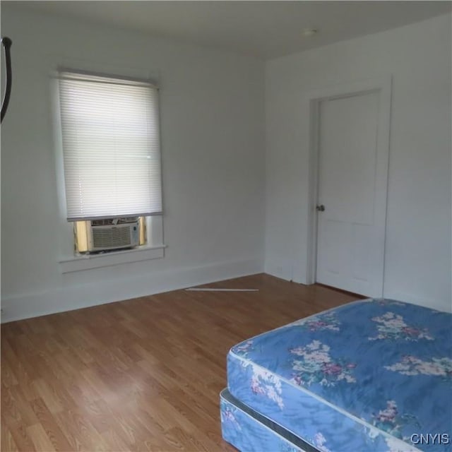 bedroom with wood finished floors, cooling unit, and baseboards