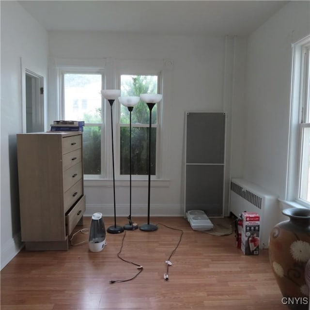 unfurnished bedroom featuring radiator heating unit, light wood-type flooring, and baseboards