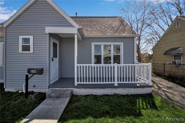 bungalow with fence, a porch, and roof with shingles