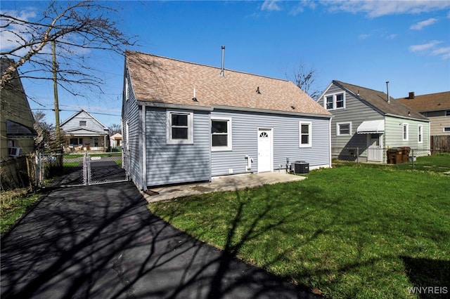 back of house featuring a yard, a gate, fence, roof with shingles, and cooling unit