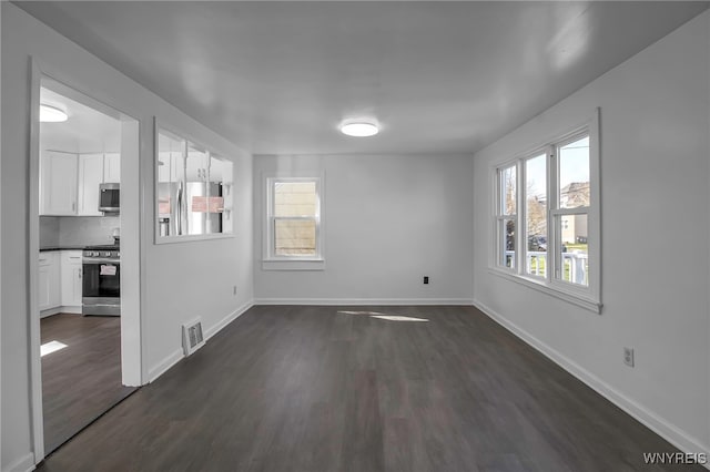 unfurnished dining area featuring dark wood-type flooring, visible vents, and baseboards