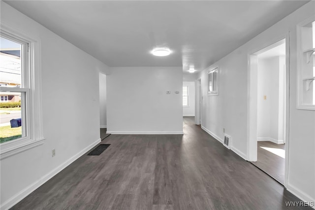 empty room with baseboards, visible vents, and dark wood-type flooring