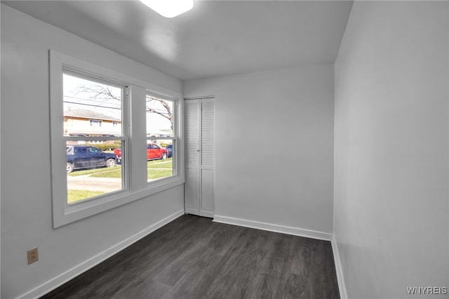 spare room featuring a healthy amount of sunlight, dark wood finished floors, and baseboards