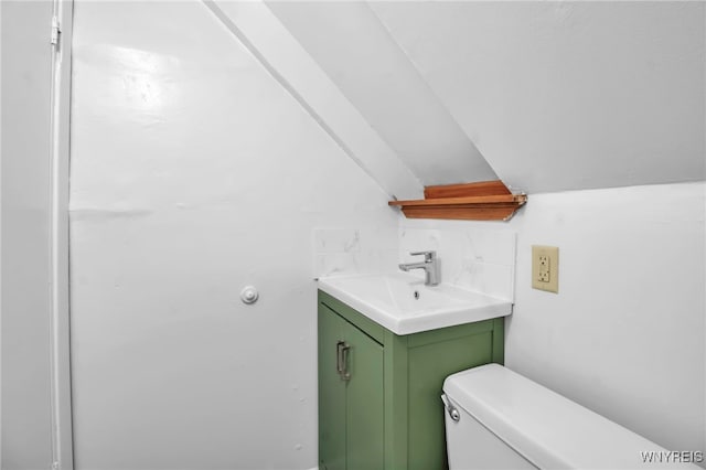 bathroom featuring toilet, vanity, and vaulted ceiling