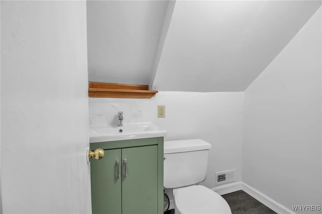 bathroom with toilet, visible vents, vanity, and baseboards