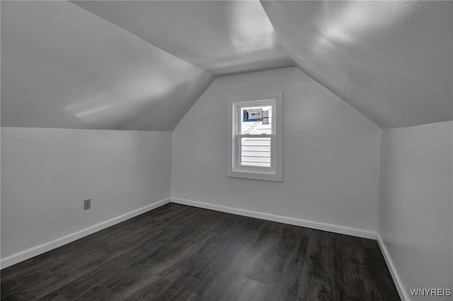 additional living space with lofted ceiling, dark wood finished floors, and baseboards