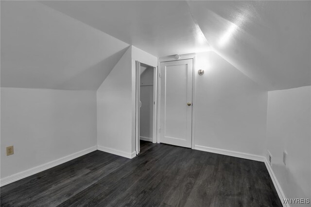 bonus room featuring lofted ceiling, dark wood-type flooring, and baseboards