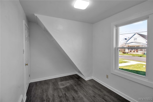 spare room with dark wood-type flooring, baseboards, and a healthy amount of sunlight