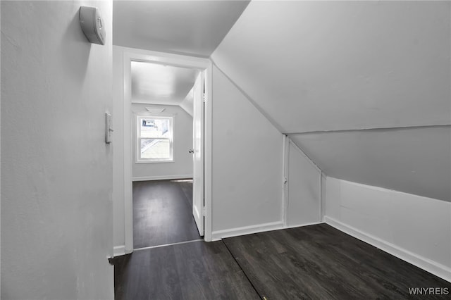 additional living space with dark wood finished floors, baseboards, and vaulted ceiling