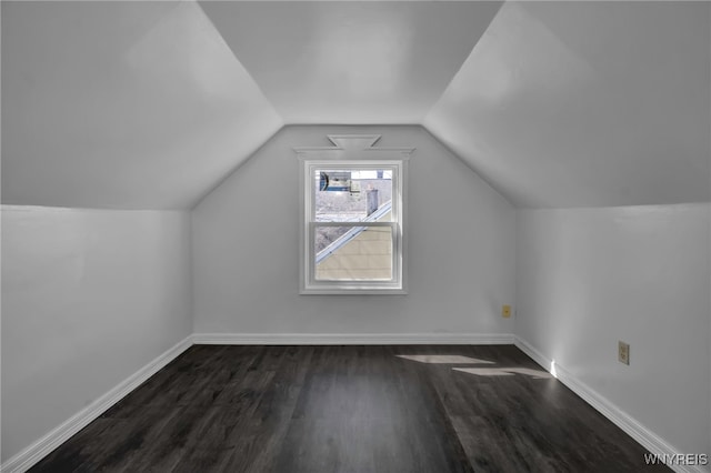 additional living space with baseboards, vaulted ceiling, and dark wood finished floors