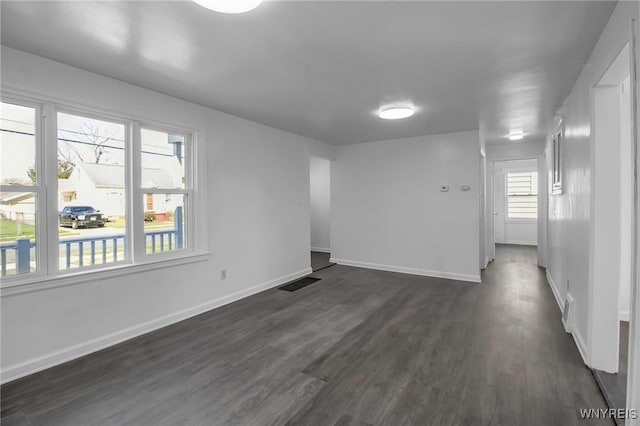 empty room with visible vents, baseboards, and dark wood finished floors