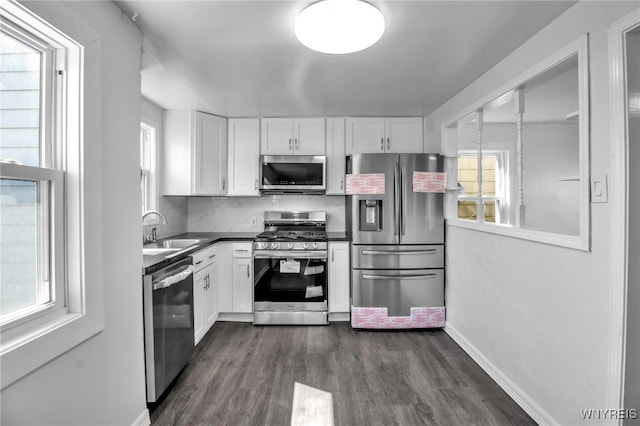 kitchen with dark countertops, stainless steel appliances, white cabinetry, and a sink