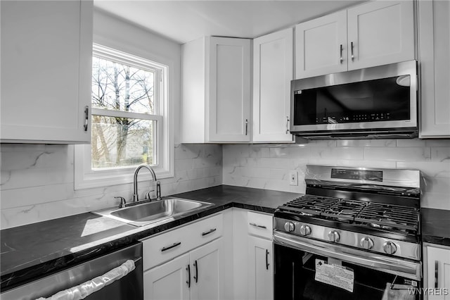 kitchen with dark countertops, a sink, white cabinets, and stainless steel appliances