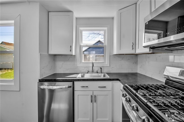 kitchen featuring appliances with stainless steel finishes, dark countertops, tasteful backsplash, and a sink
