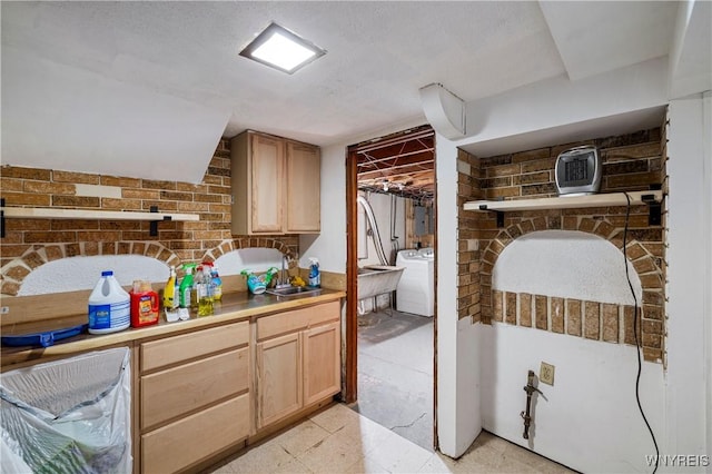 interior space with light brown cabinetry, washer / clothes dryer, and a sink