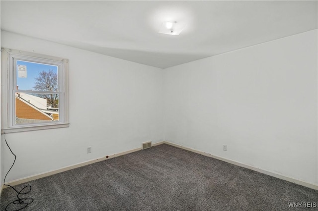 empty room with baseboards, dark colored carpet, and visible vents