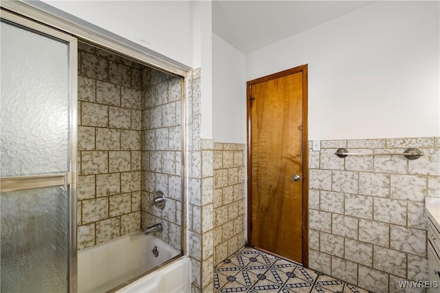 bathroom featuring a wainscoted wall, enclosed tub / shower combo, tile walls, tile patterned floors, and vanity