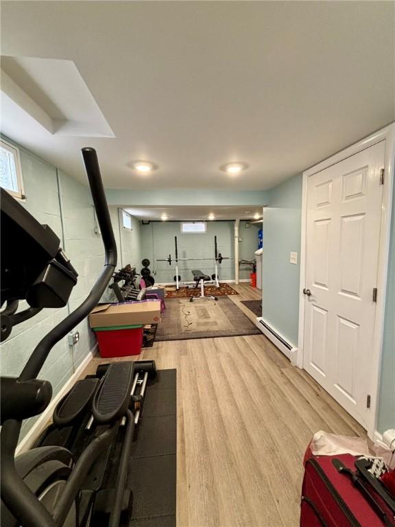 exercise area with wood finished floors and a baseboard heating unit