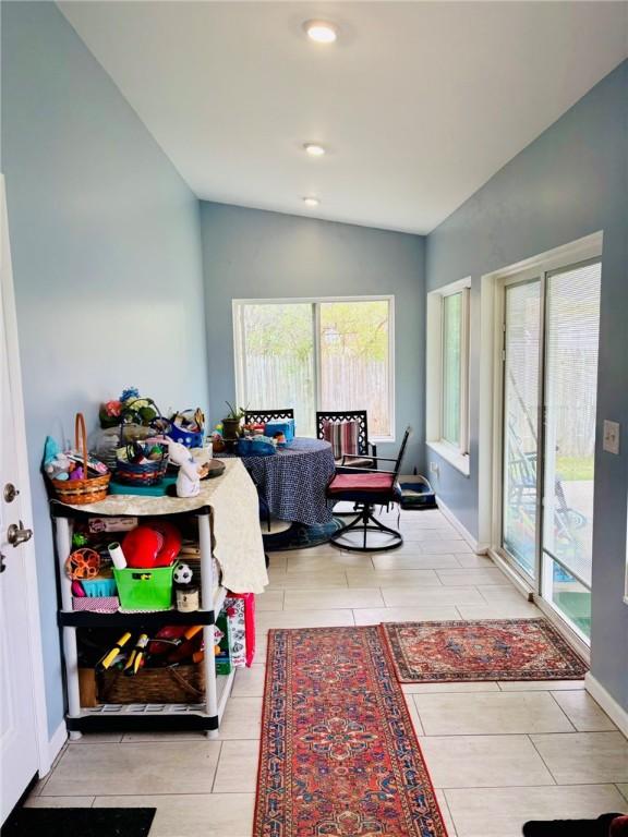 living area with vaulted ceiling, a wealth of natural light, and tile patterned floors