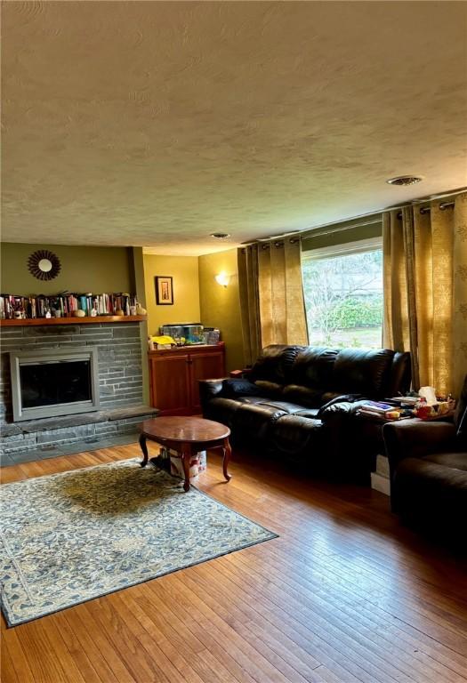 living room with a stone fireplace and wood-type flooring