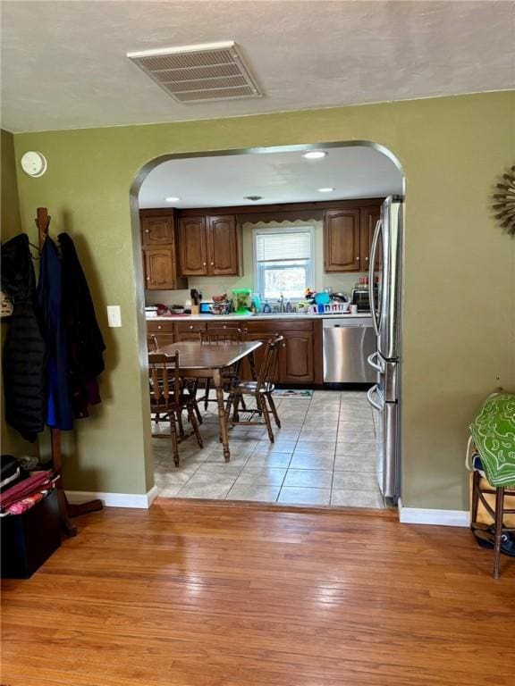 kitchen with stainless steel appliances, visible vents, baseboards, light countertops, and arched walkways