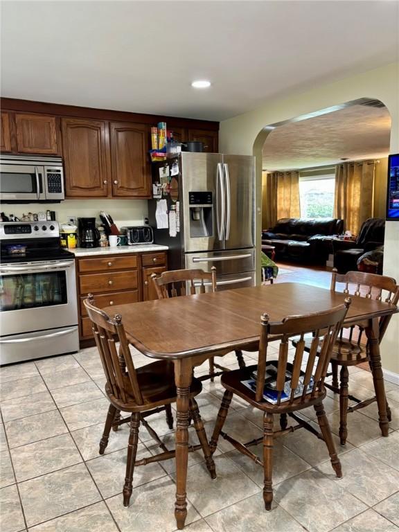 kitchen with recessed lighting, arched walkways, light tile patterned floors, appliances with stainless steel finishes, and light countertops