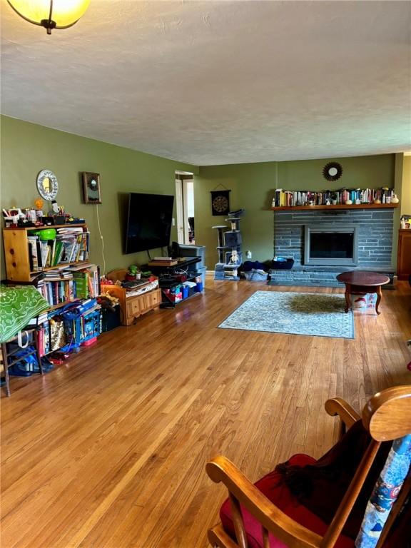 living room featuring a fireplace with raised hearth, a textured ceiling, and wood finished floors