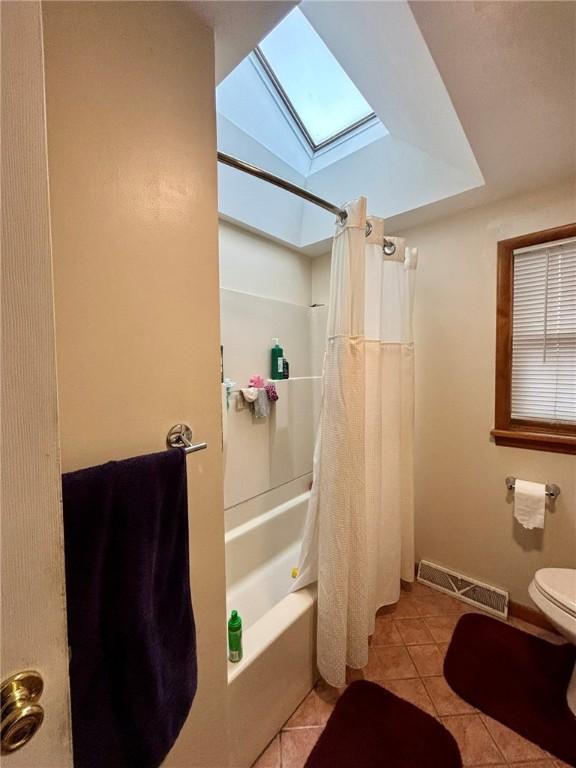 bathroom featuring a skylight, tile patterned flooring, toilet, visible vents, and shower / tub combo