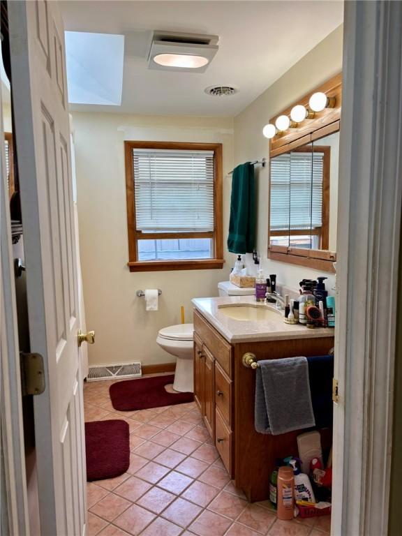 bathroom with tile patterned floors, toilet, vanity, baseboards, and visible vents