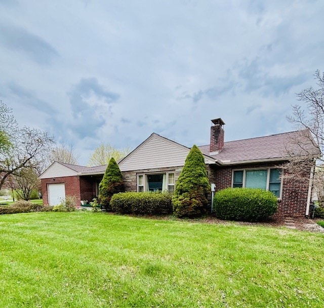 ranch-style home with a chimney, brick siding, a front yard, and an attached garage