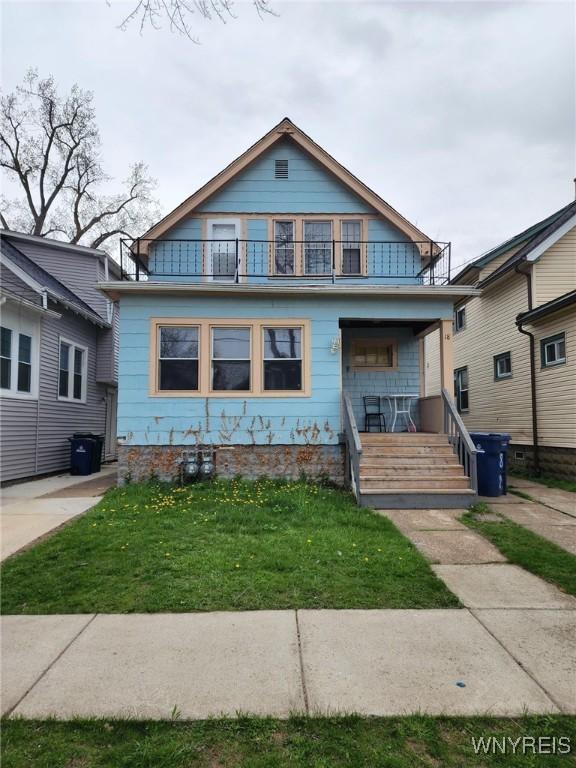 bungalow with covered porch, a front lawn, and a balcony
