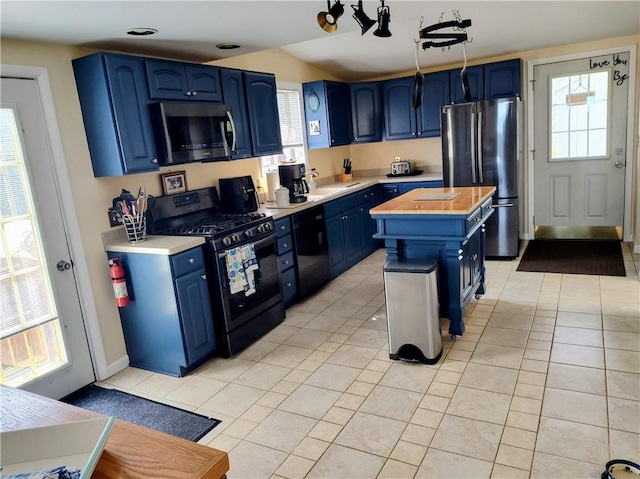 kitchen featuring black appliances, blue cabinetry, light countertops, and a sink