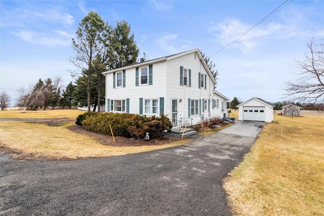 view of front of home with an outdoor structure, a detached garage, driveway, and a front yard