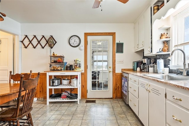 2481 County Road 20, Phelps, NY 14432 - kitchen featuring a sink, ceiling fan, white cabinets, light countertops, and a wainscoted wall
