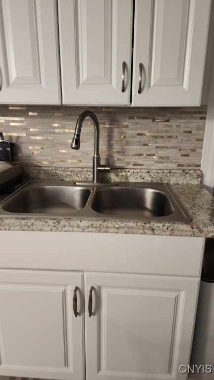 details with white cabinetry, tasteful backsplash, dishwasher, and a sink