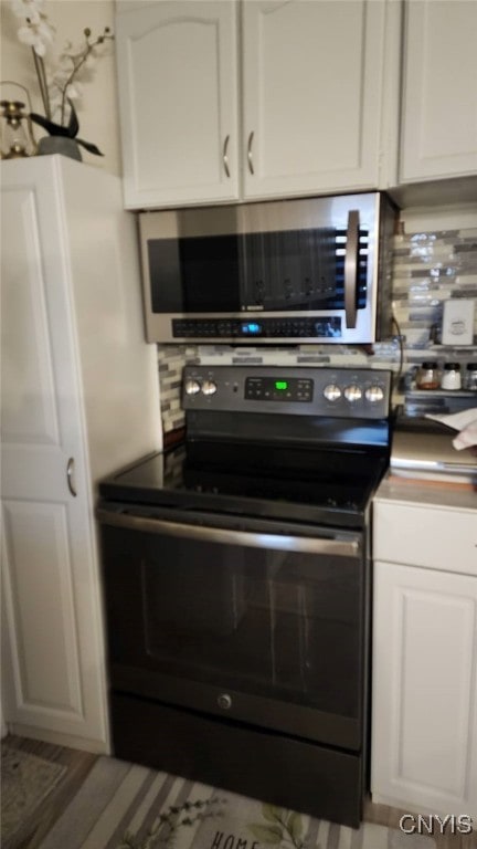 kitchen featuring tasteful backsplash, electric range, white cabinets, and stainless steel microwave
