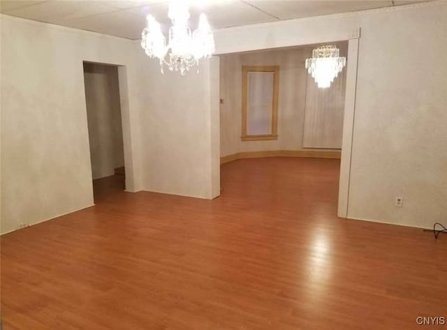 empty room with an inviting chandelier and wood finished floors