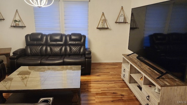 living room featuring baseboards, wood finished floors, and an inviting chandelier