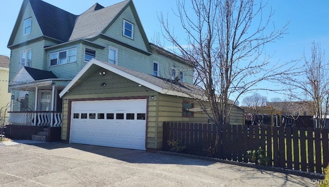 view of front of property with a garage, fence, a shingled roof, and driveway