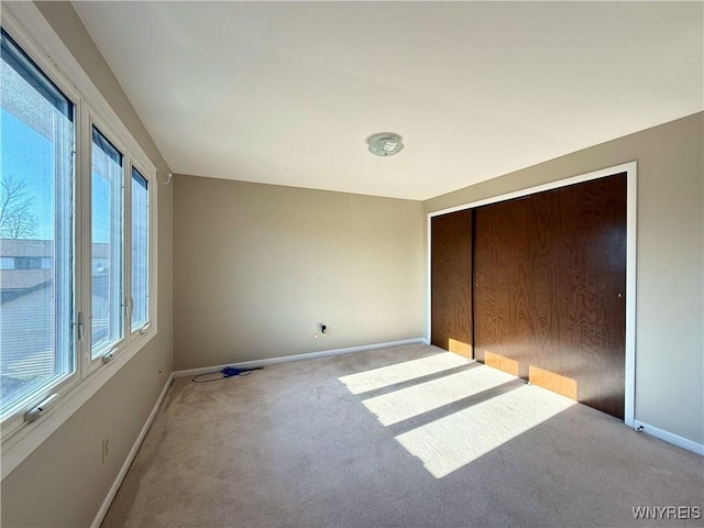 unfurnished bedroom with a closet, carpet flooring, and baseboards