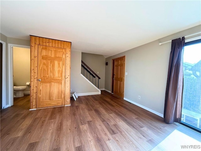 spare room featuring stairs, wood finished floors, and baseboards