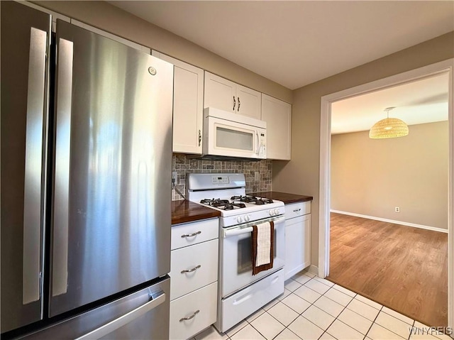 kitchen featuring tasteful backsplash, white appliances, light tile patterned floors, white cabinets, and baseboards
