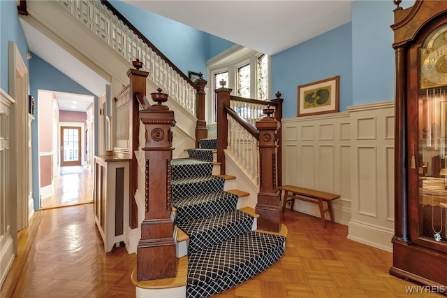 stairs with wainscoting, a healthy amount of sunlight, and a decorative wall